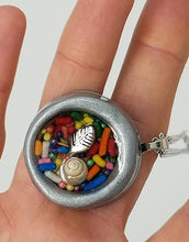 Load image into Gallery viewer, Round gray clay pendant filled with real candy sprinkles, metal leaf and tiny seashell immersed in resin - Includes chain - Curio Memento
